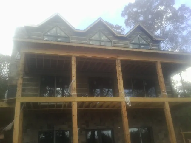 Dormers and porch framing on a large log home under construction — Roof Coating work by our crew in Flint