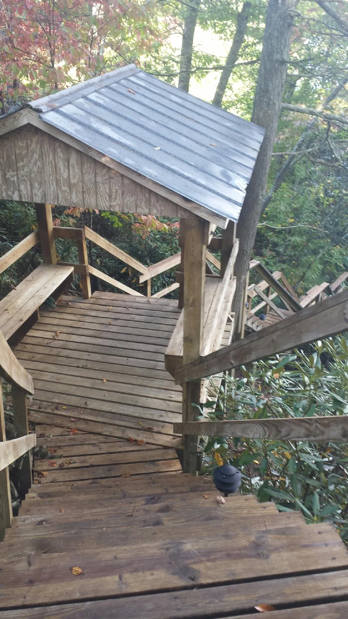 Metal roofed shelter over wooden steps on a wooded walkway — Skylight Repair & Installation work by our crew in Flint